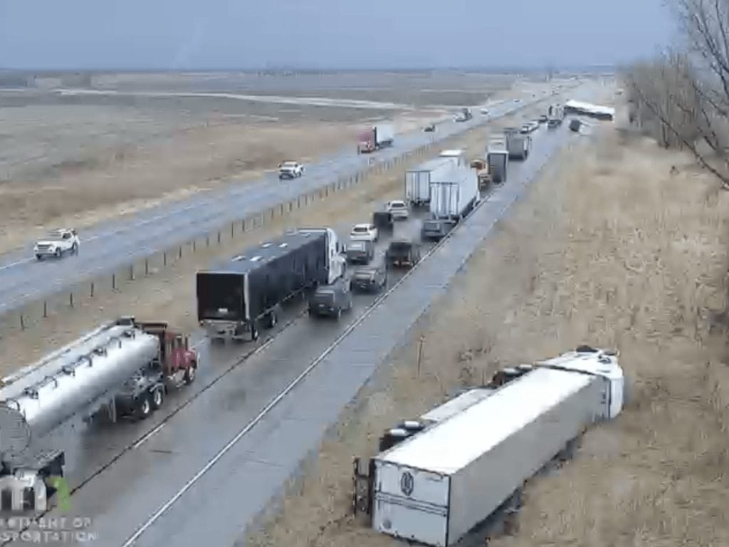 Traffic accident scene with overturned semi-truck near the highway.